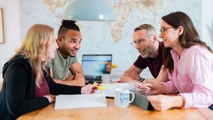 Studierende sitzen am Tisch, lernen und unterhalten sich