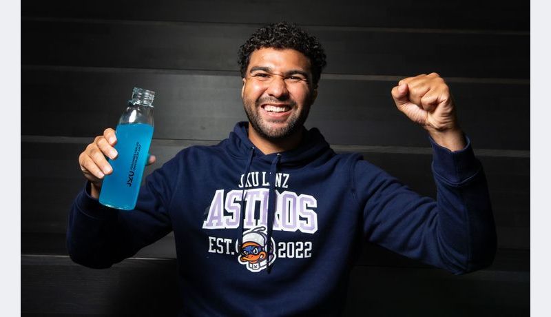 Ein Mann mit JKU und JKU Astros Merchandise
